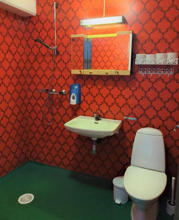 An old bathroom with red patterned wallpaper, before the renovation
