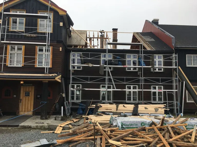 The main house under renovation, wrapped in scaffolding with timber stacked outside